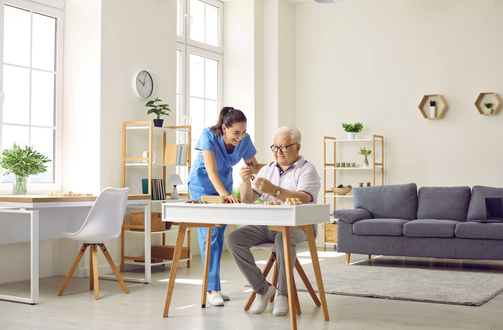 An older adult man trying to solve a puzzle with the assistance of a memory care home staff.