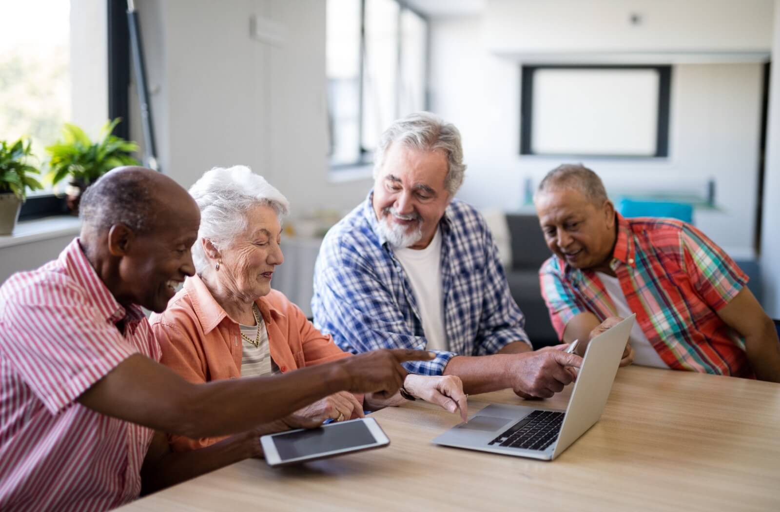 A group of older adults watching a video on a laptop.