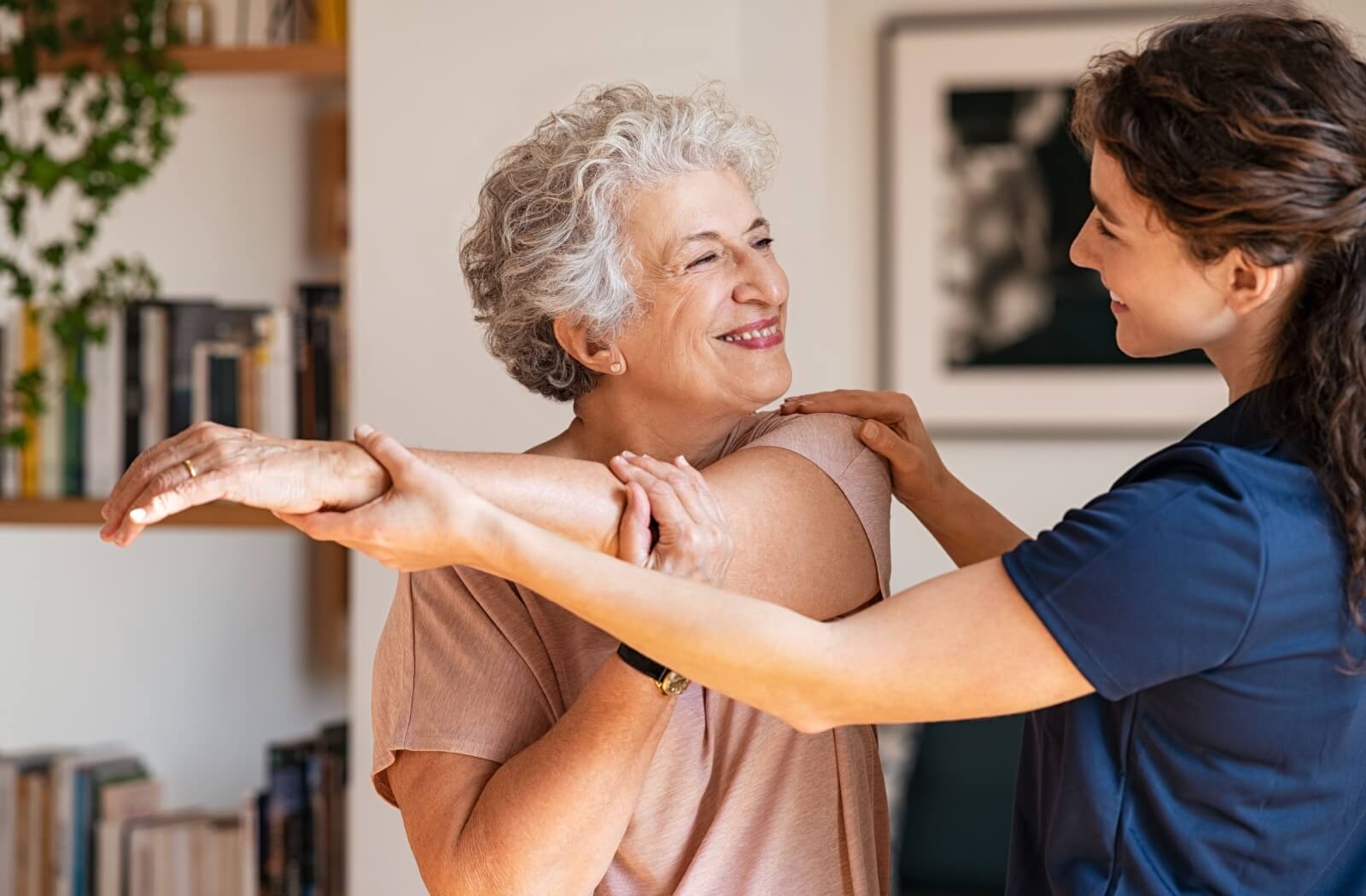 A personal care home staff helping a resident to stretch her arm.