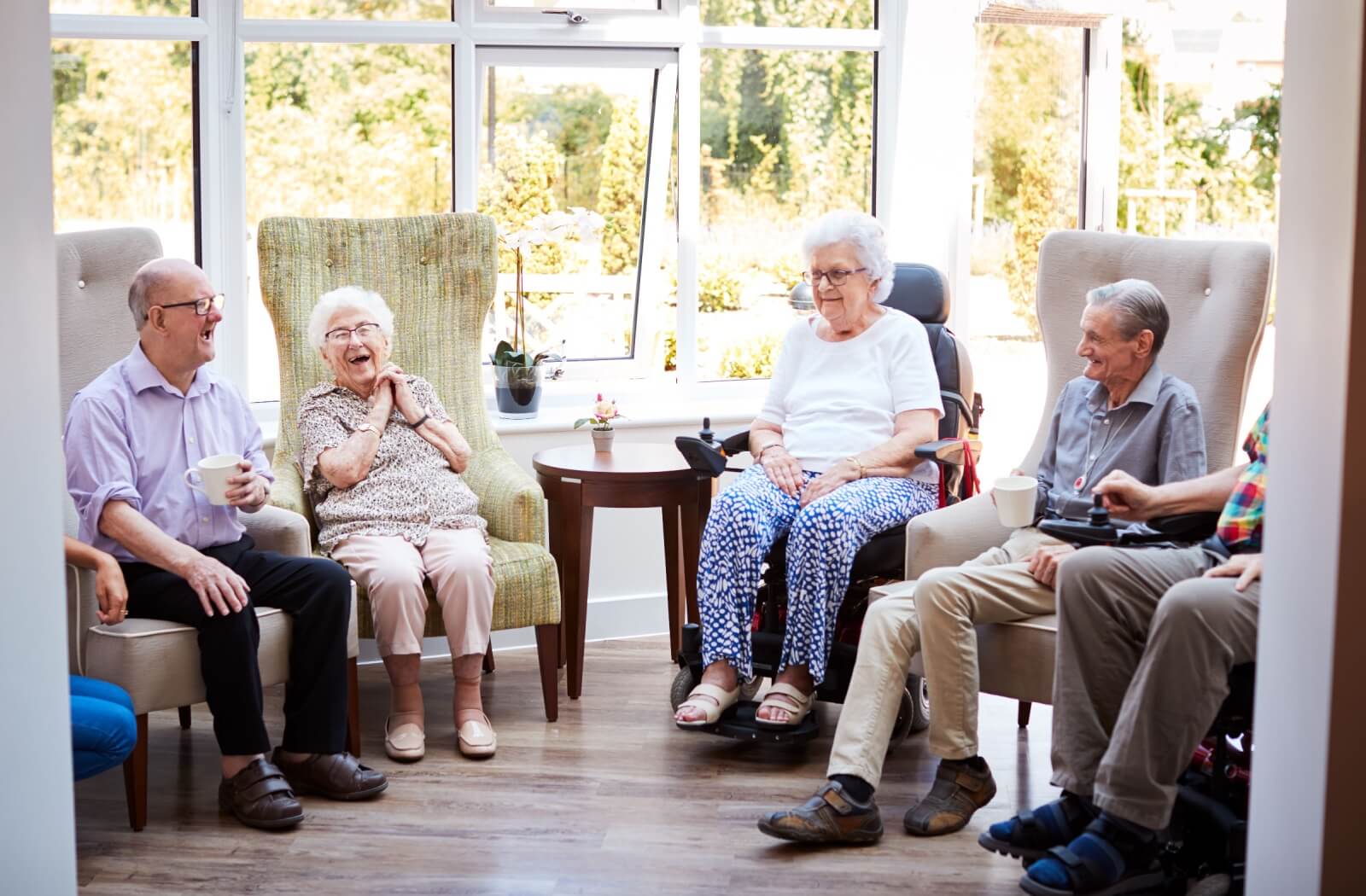 A group of older adults enjoying a conversation as they sit in a common area of a personal care community.