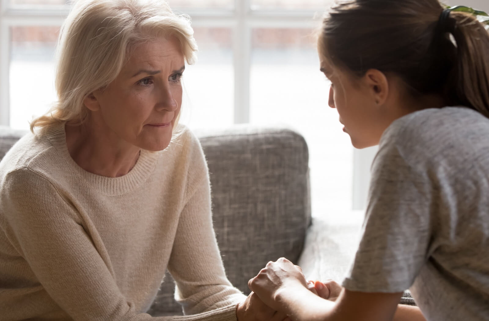 Adult daughter holding her elderly mother's hands, showing support and care.