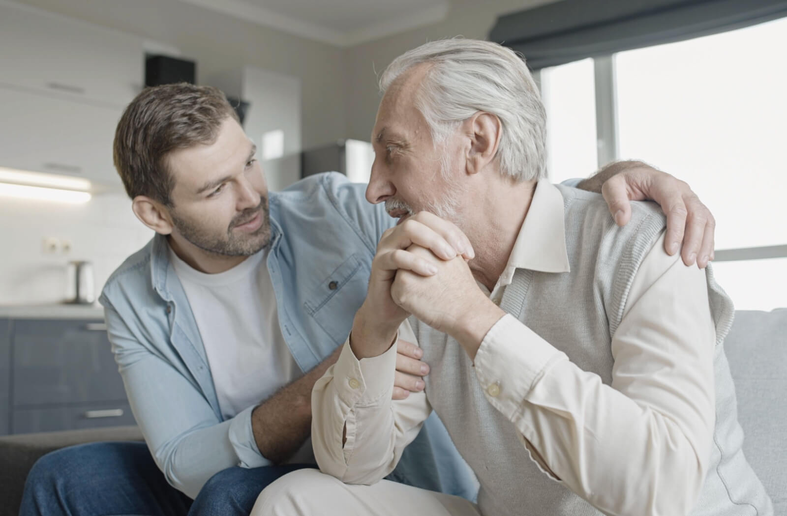 A caring son providing emotional support by hugging his father's shoulders, demonstrating care as they discuss guardianship matters.