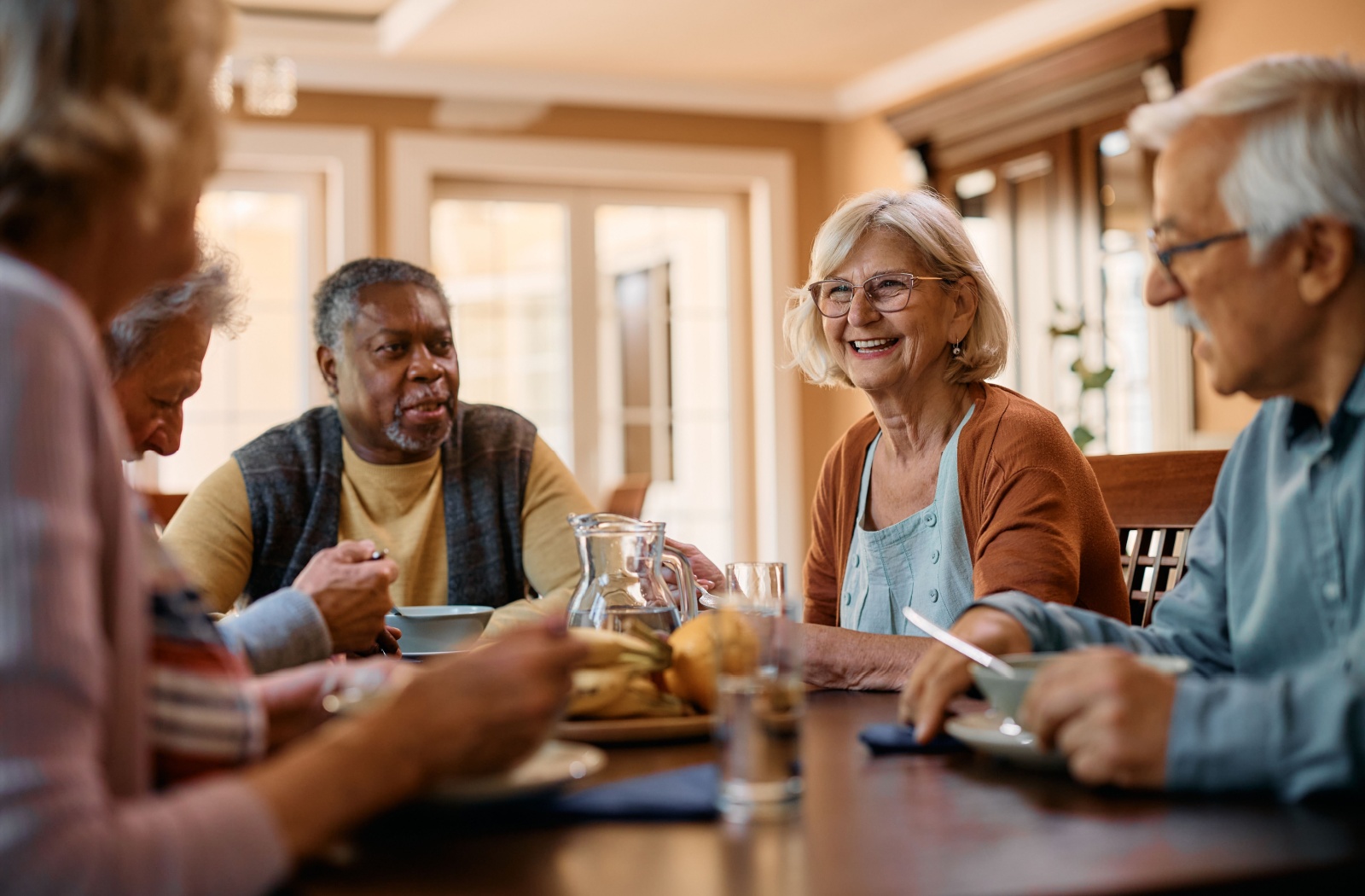 A group of older adults enjoying a meal together in the dining room of their independent living community