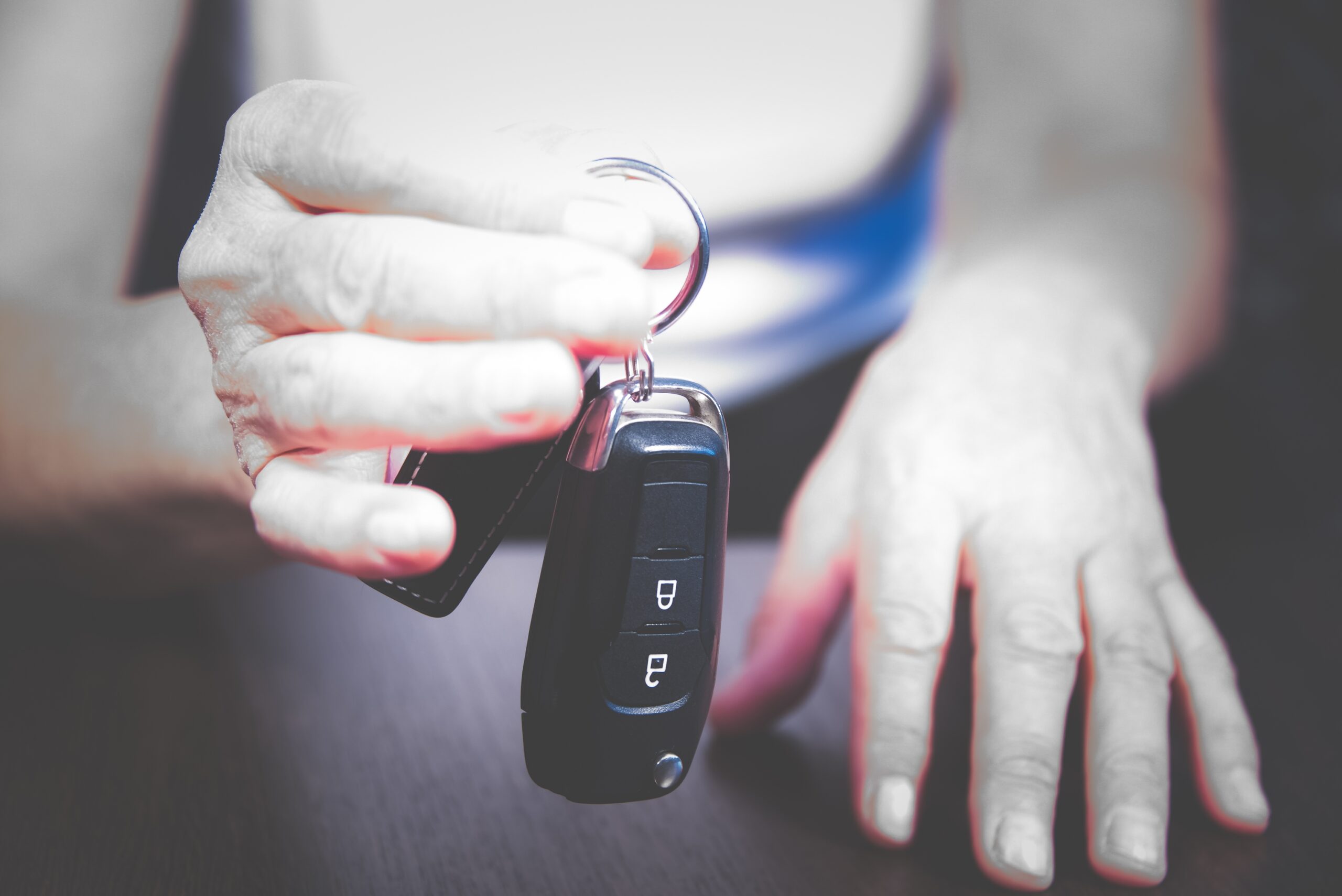 An older adult woman's hands holding a set of car keys.
