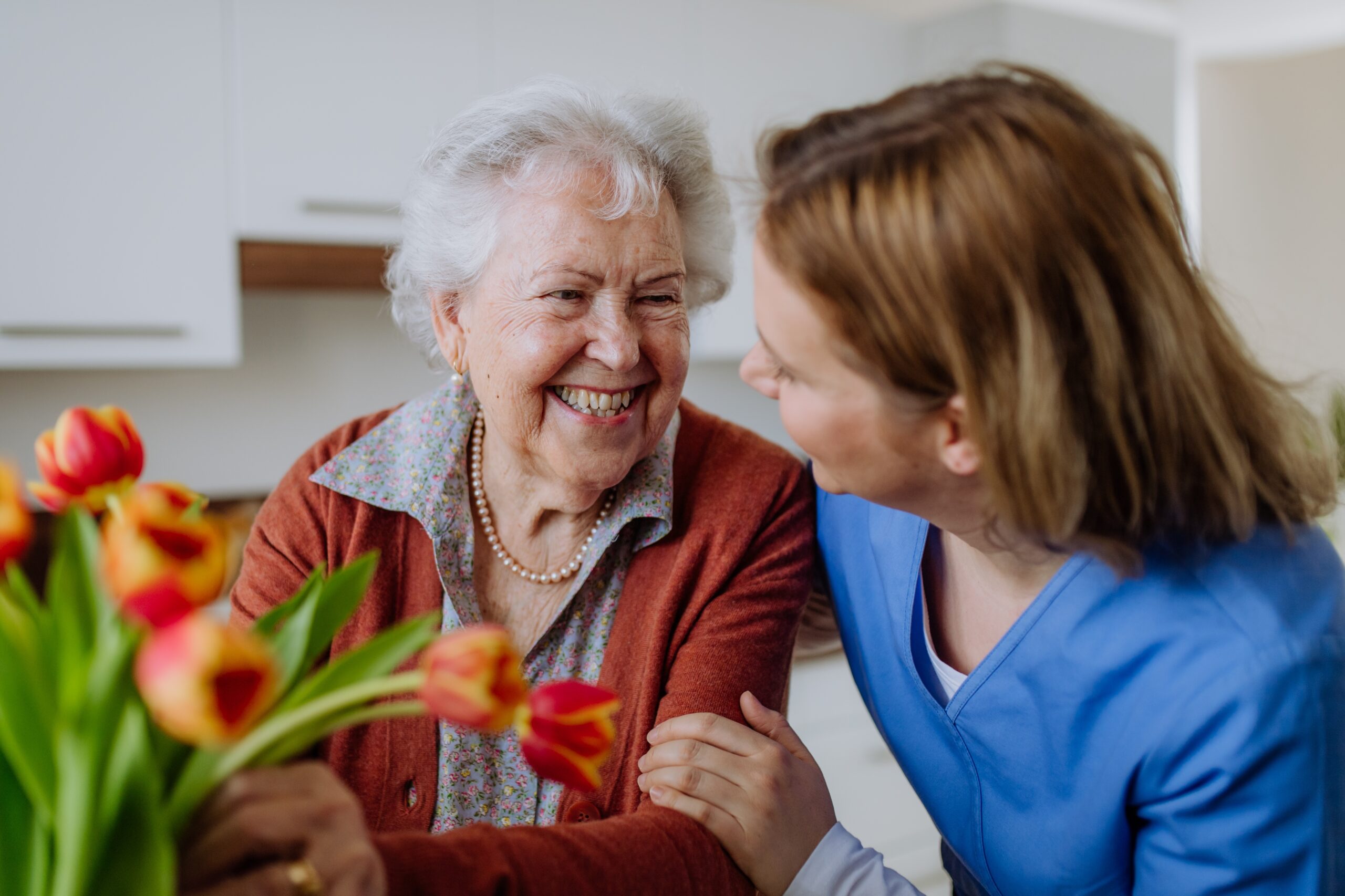A caregiver and resident bond at an assisted living community while arranging flowers together.