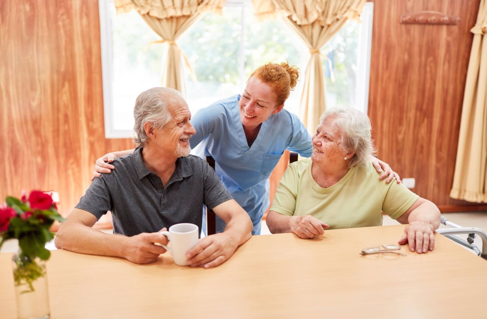 Assisted living caregiver talking to an older adult couple about the community.