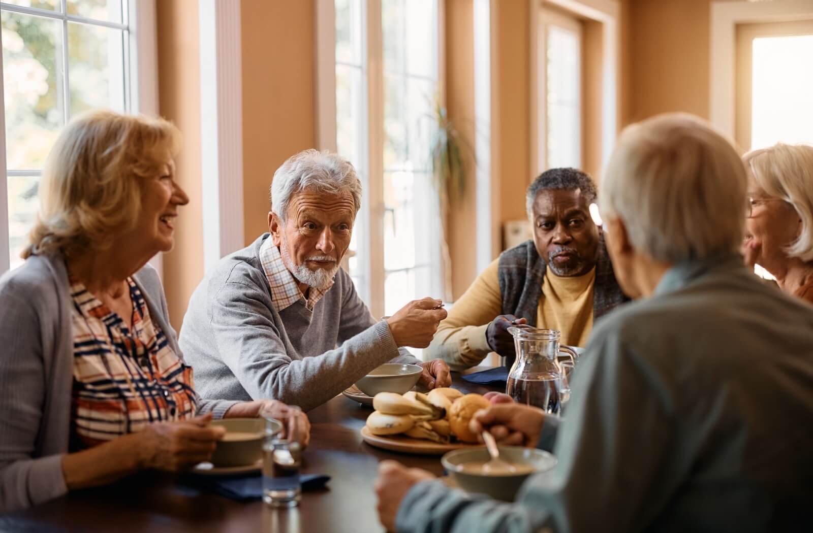 A group of cheerful-looking older adults gathered together for breakfast and conversation.
