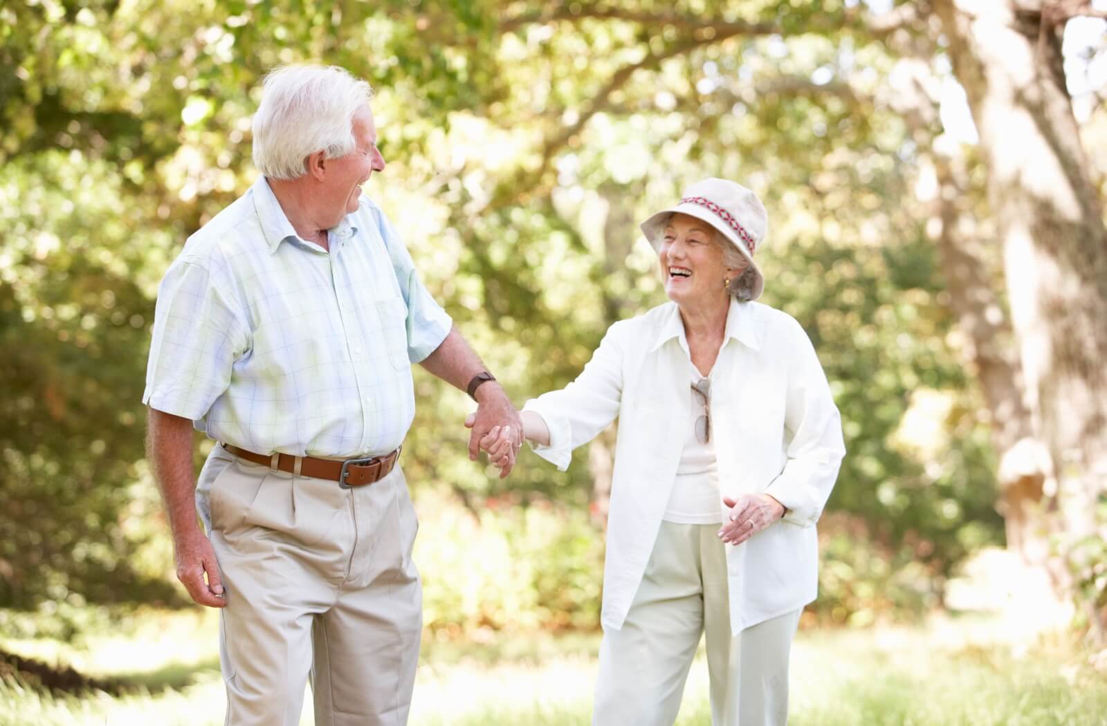 An older adult couple walking together hand-in-hand in a community garden.