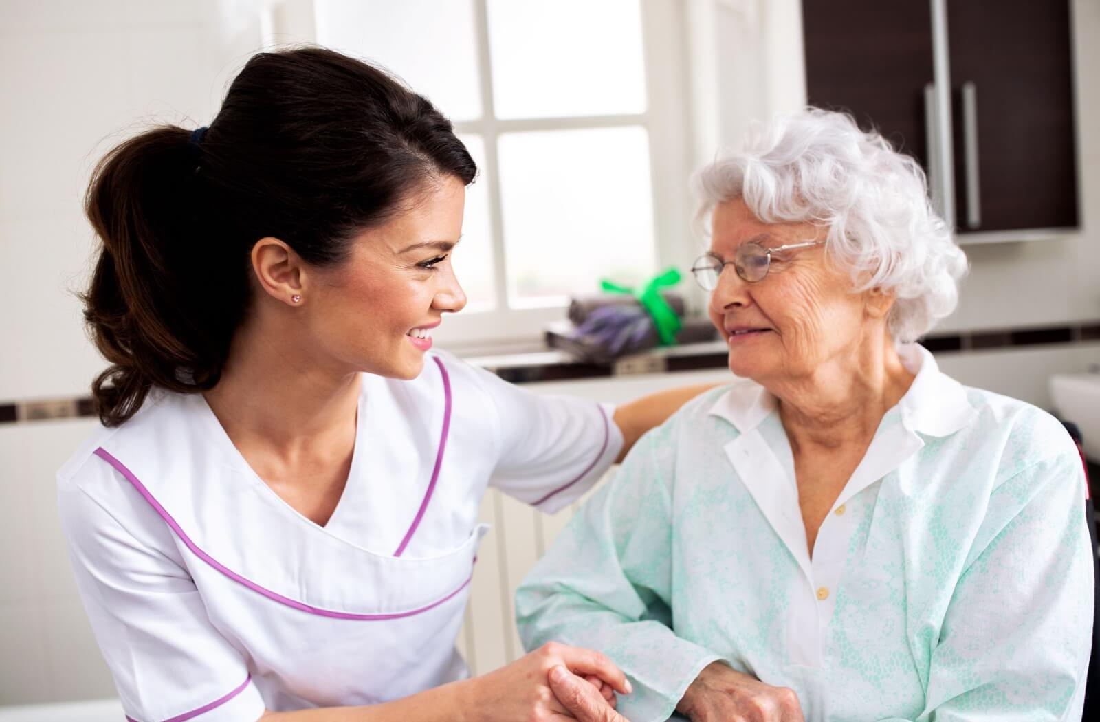 A caregiver provides personalized support to an older adult woman in assisted living.