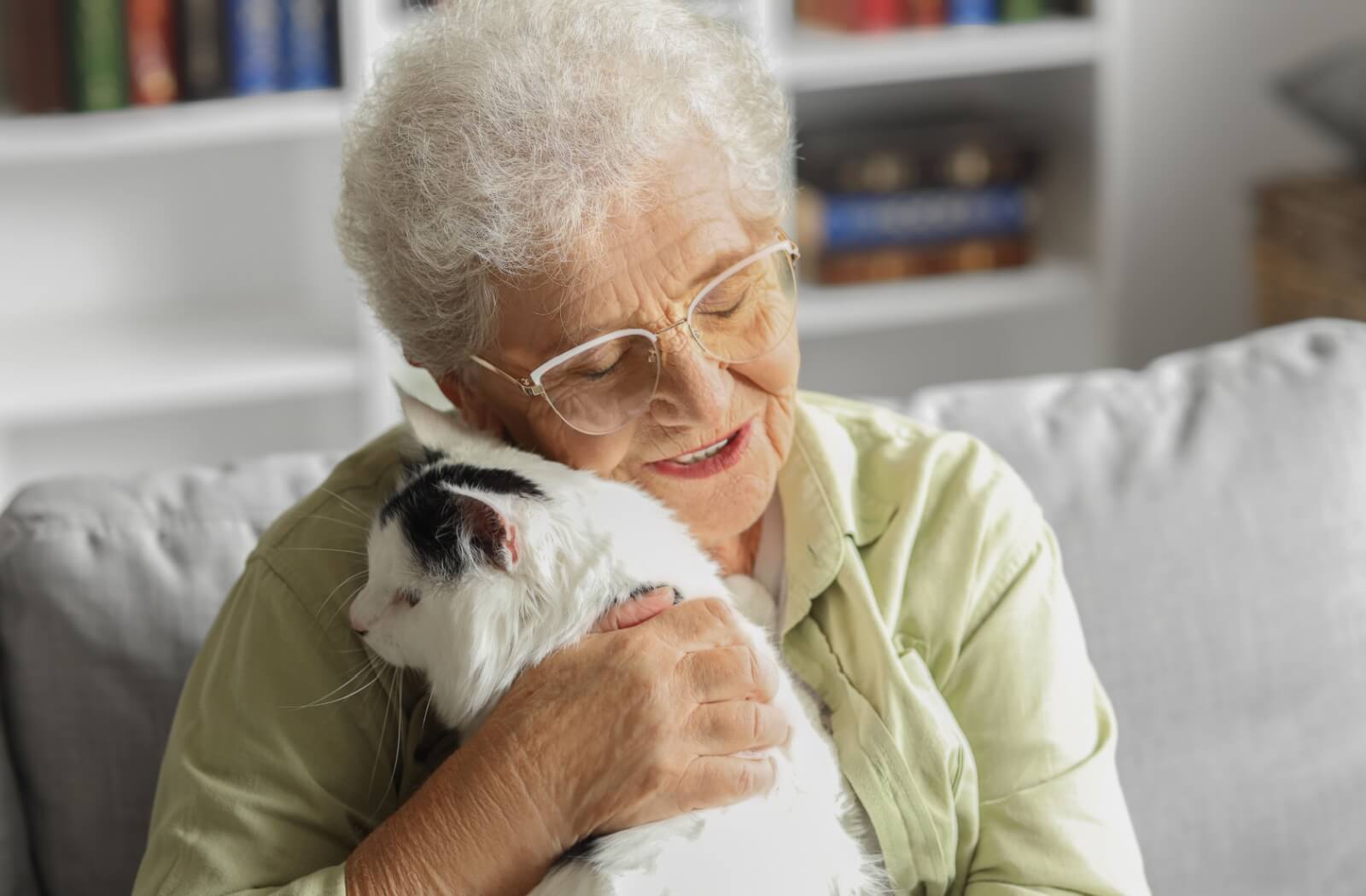 An older adult woman snuggles a cat as part of pet therapy in an assisted living community.