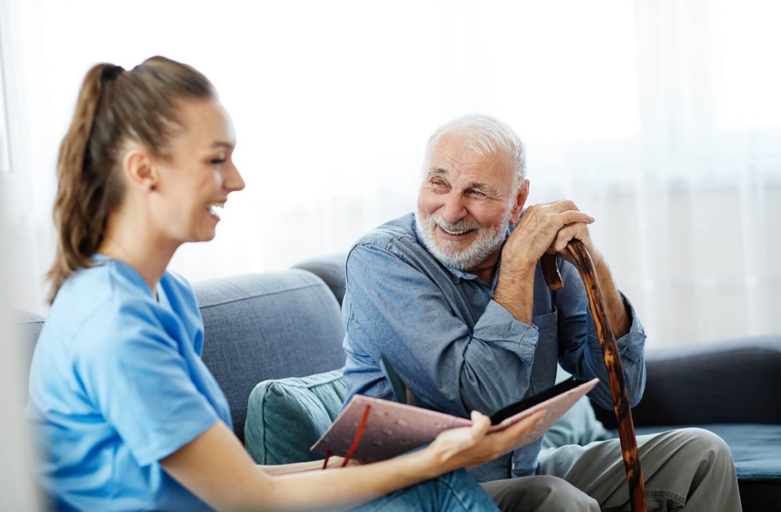 An older adult man chatting with a memory care team member as she shows him a photo album.