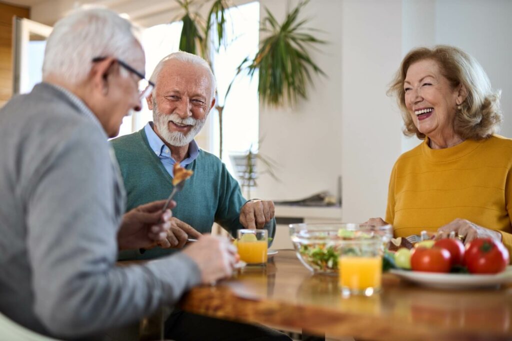 A group of older adults laughing and dining together.