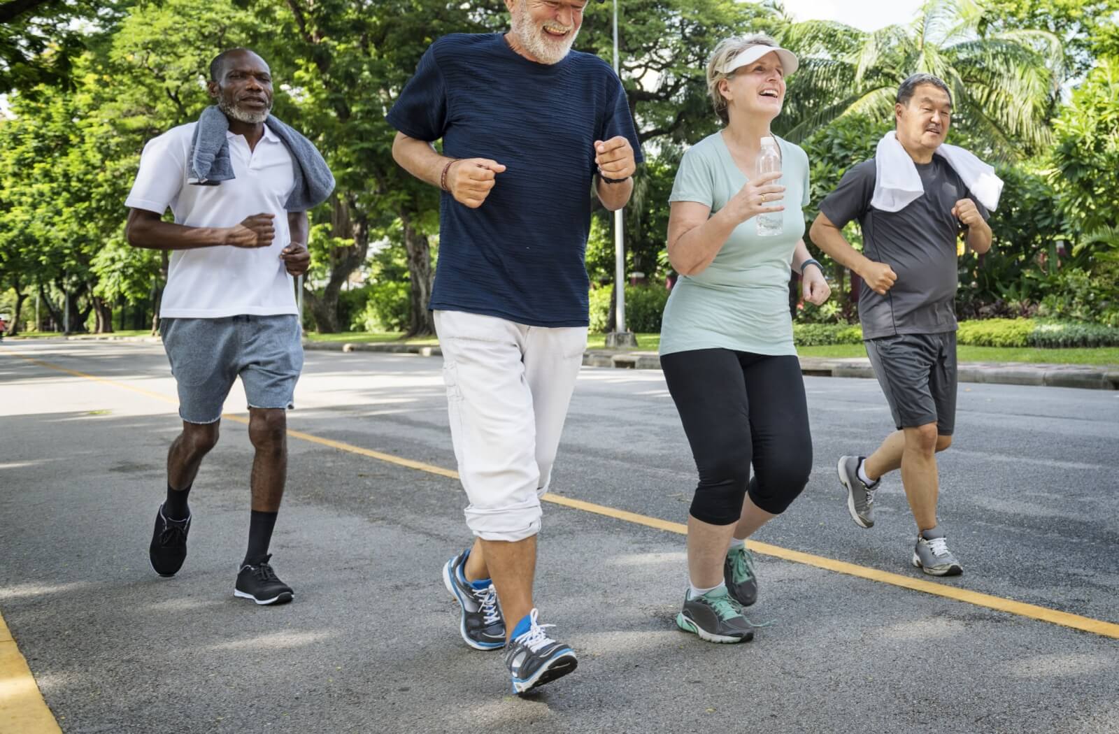 4 older adults smiling and jogging in a park