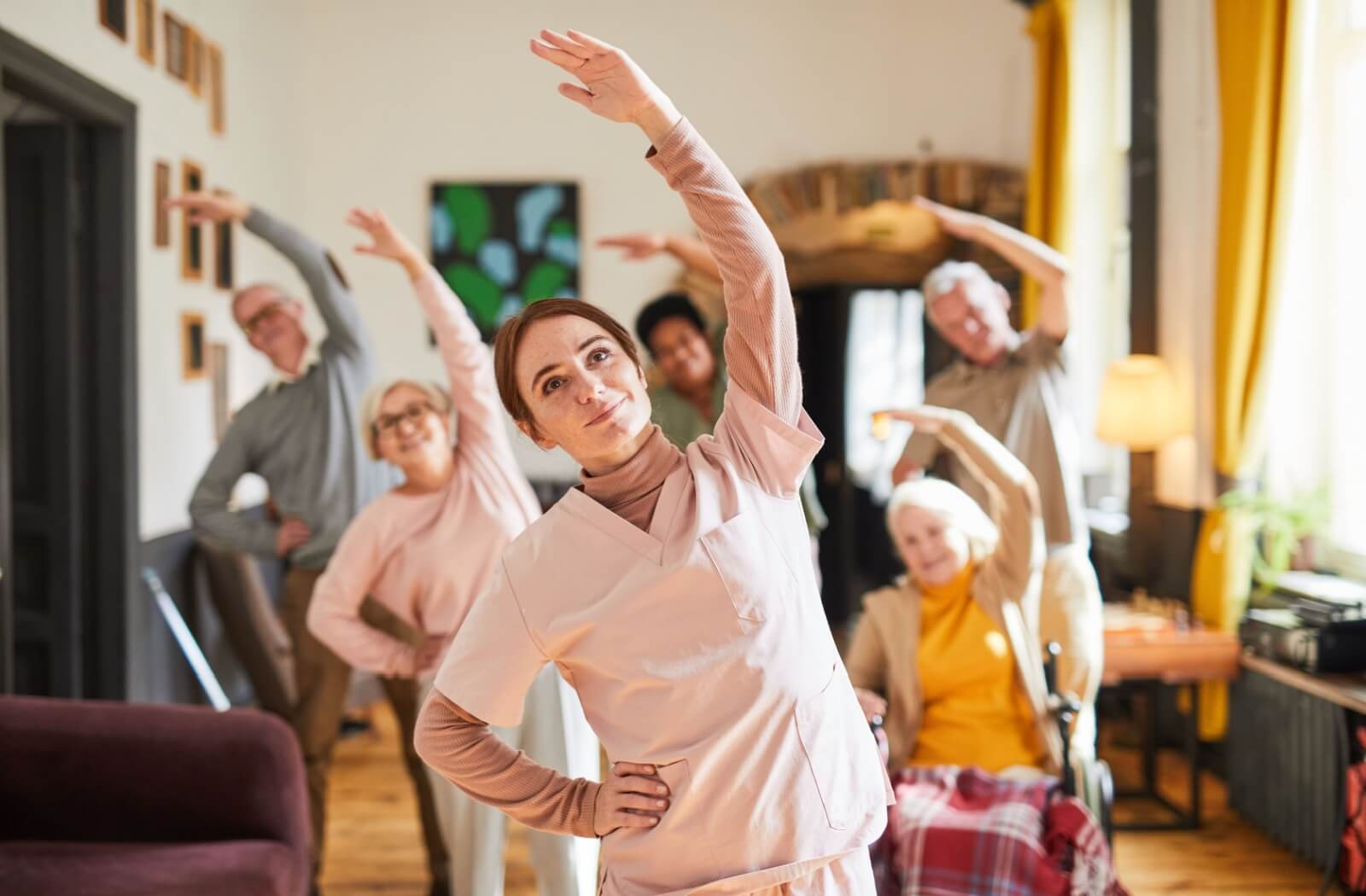 A female caregiver helping a group of older adults to stretching activity in a personal care home