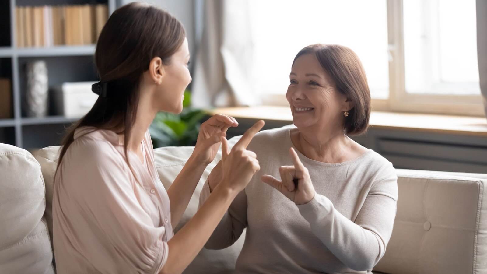 An adult daughter uses sign language to communicate with her non verbal mother.