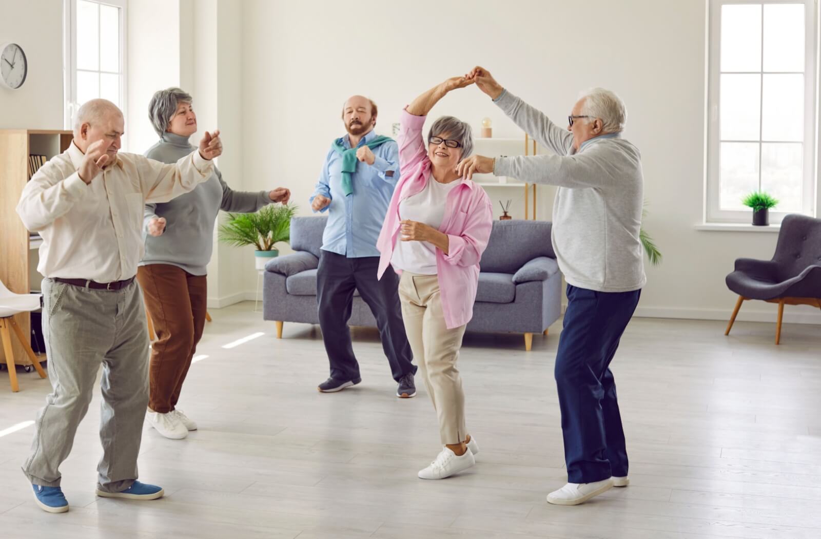 A group of older adults dance together in creative expression.