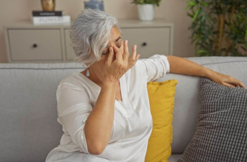 An exhausted woman with a headache closes her eyes and rubs them.