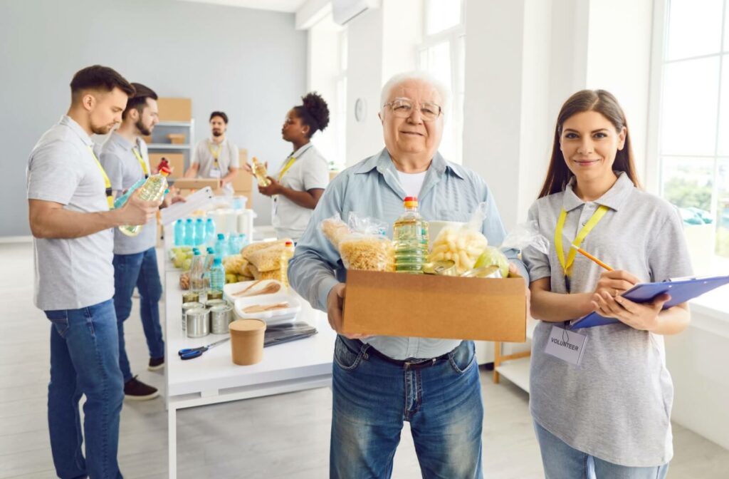 A mature man helps out younger volunteers at the food bank.