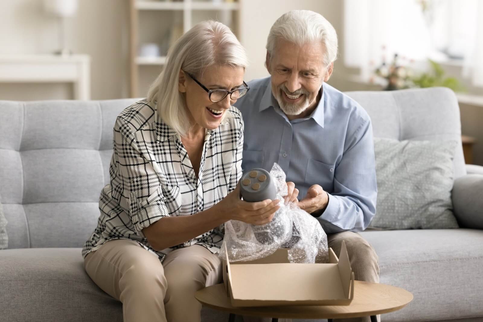 Cheerful older adult couple unpacking in their assisted living home.