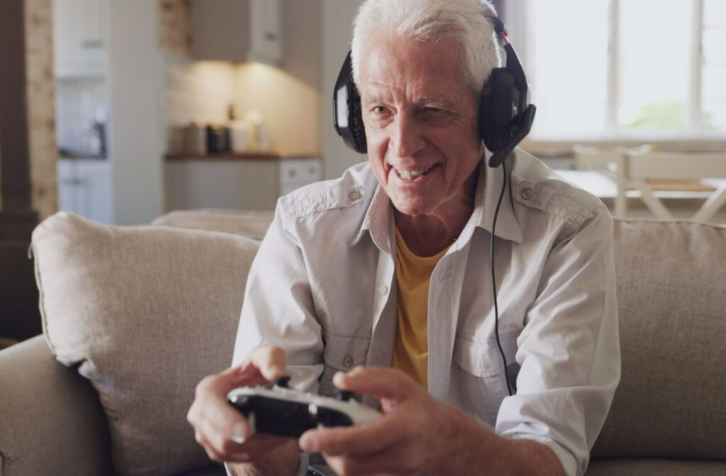 A mature man is engaged in a multiplayer online game with headphones on.
