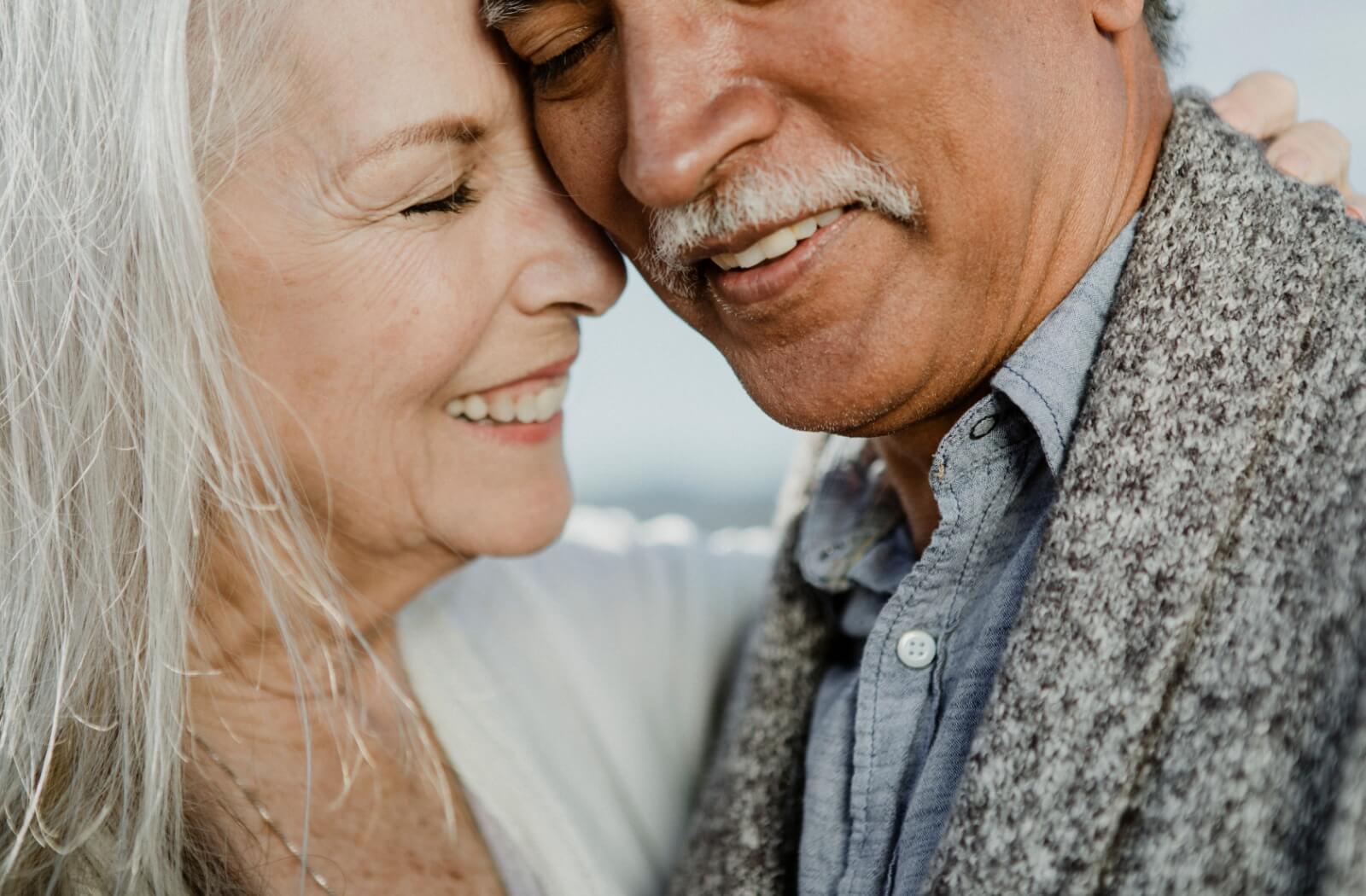 Two older adults dating smiling and embracing lovingly.