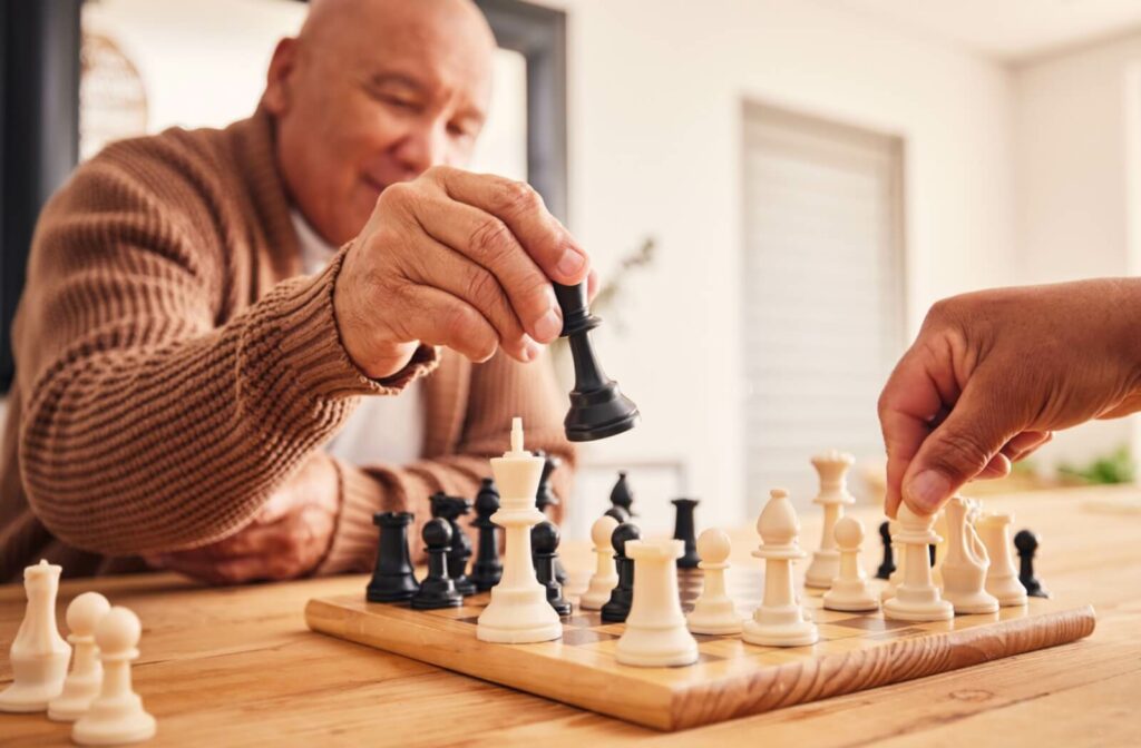An older adult moves a piece during a chess game.