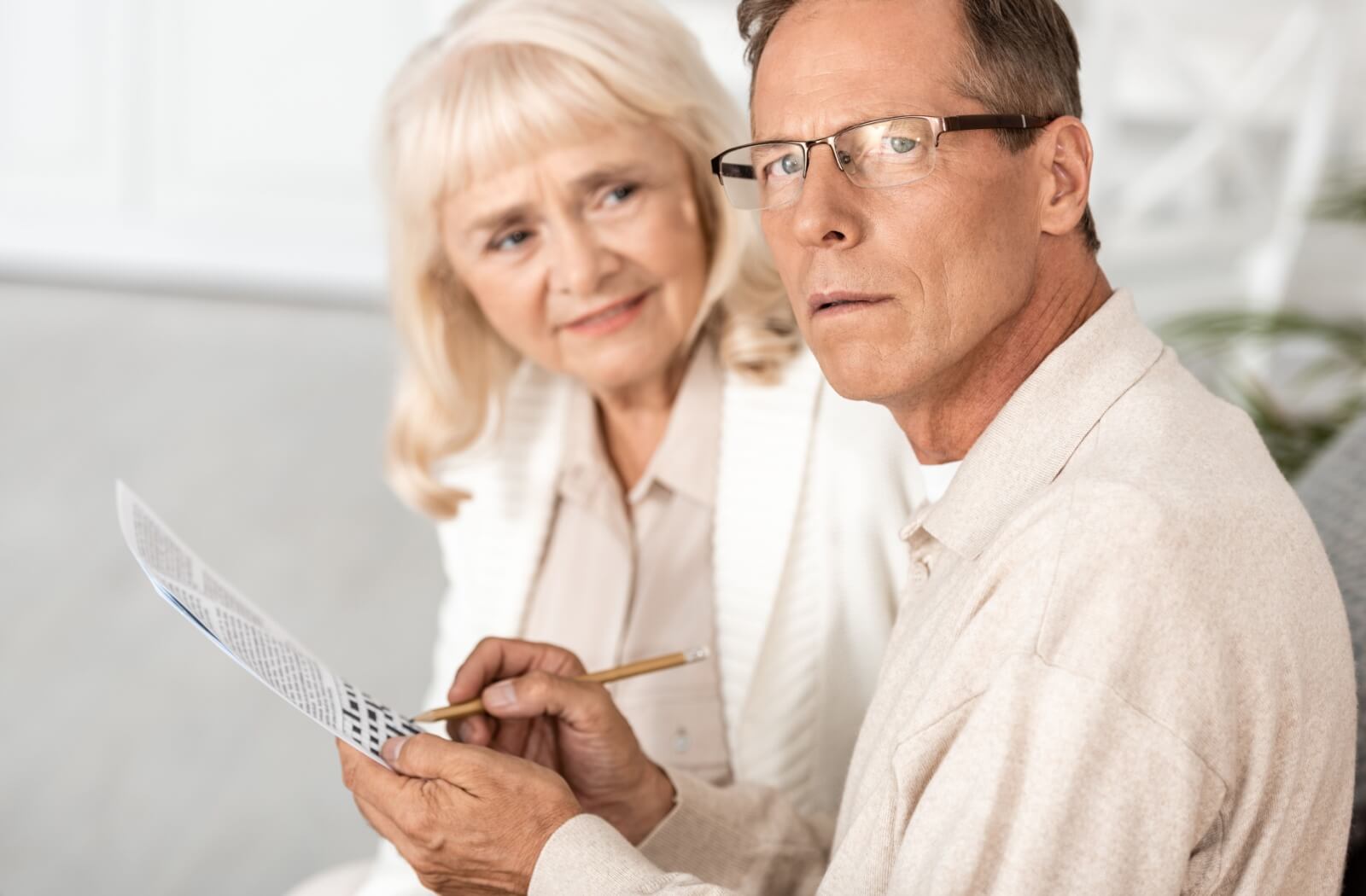 Older adult couple focused on solving a crossword puzzle together.
