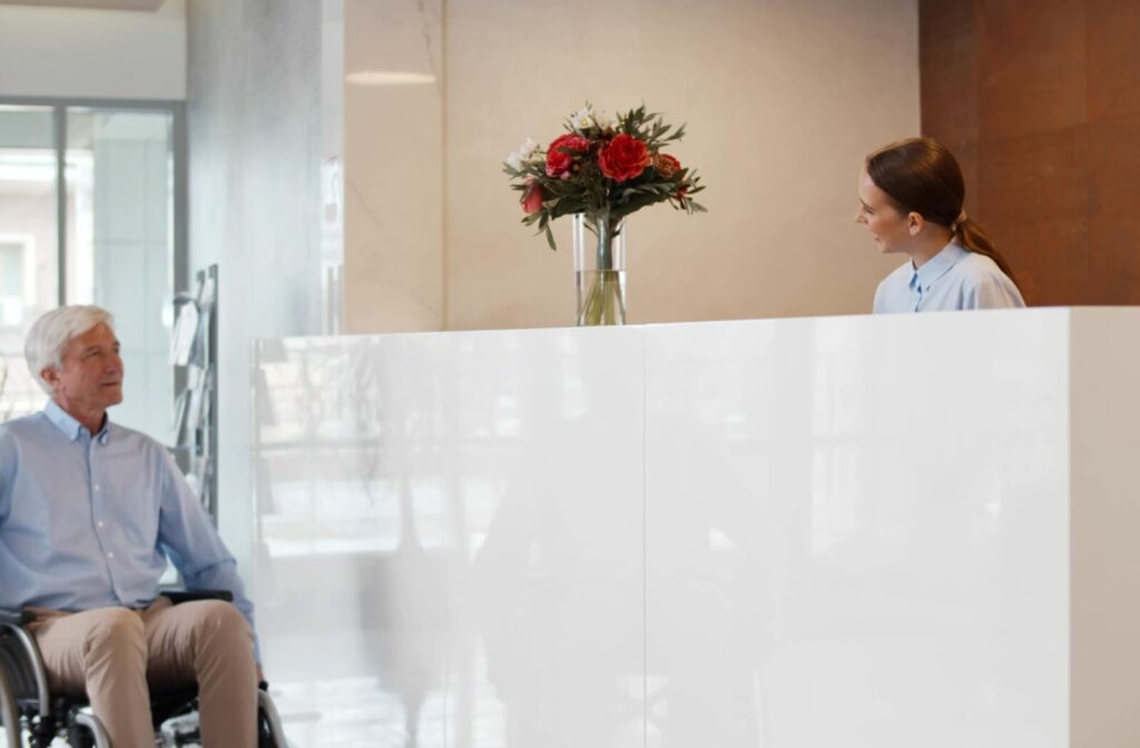 An older adult man in a wheelchair checking into his accessible hotel room.