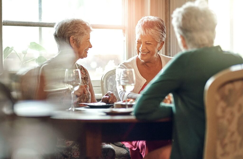 A group of older adults laughing and chatting around the dinner table.