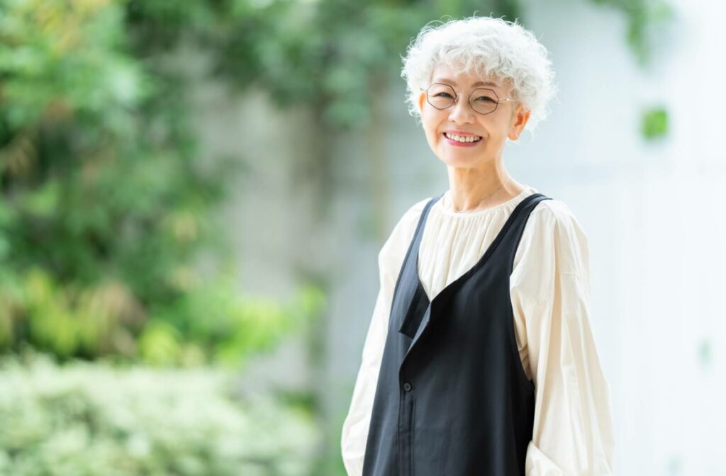 A mature woman wandering through a memory care garden with a smile.
