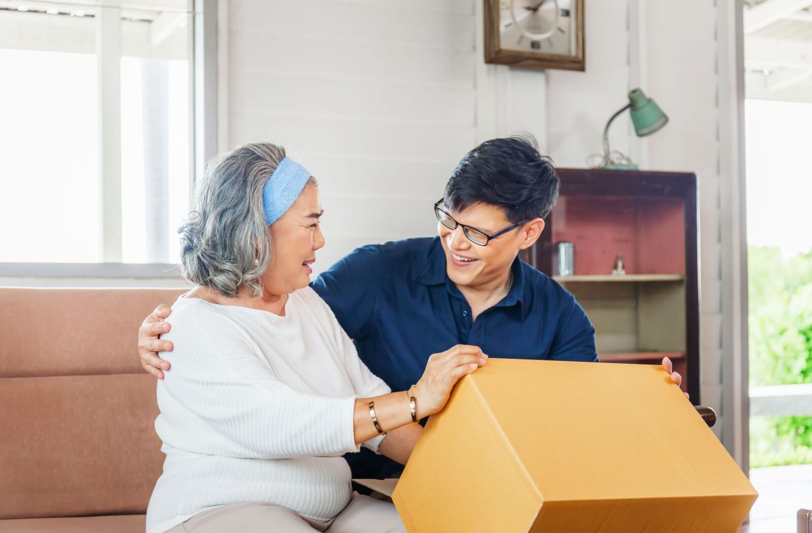 A young adult helps his older adult mother with her move to assisted living.