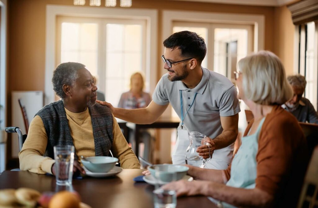 A dining room assistant serves water to residents in an independent living community dining room.