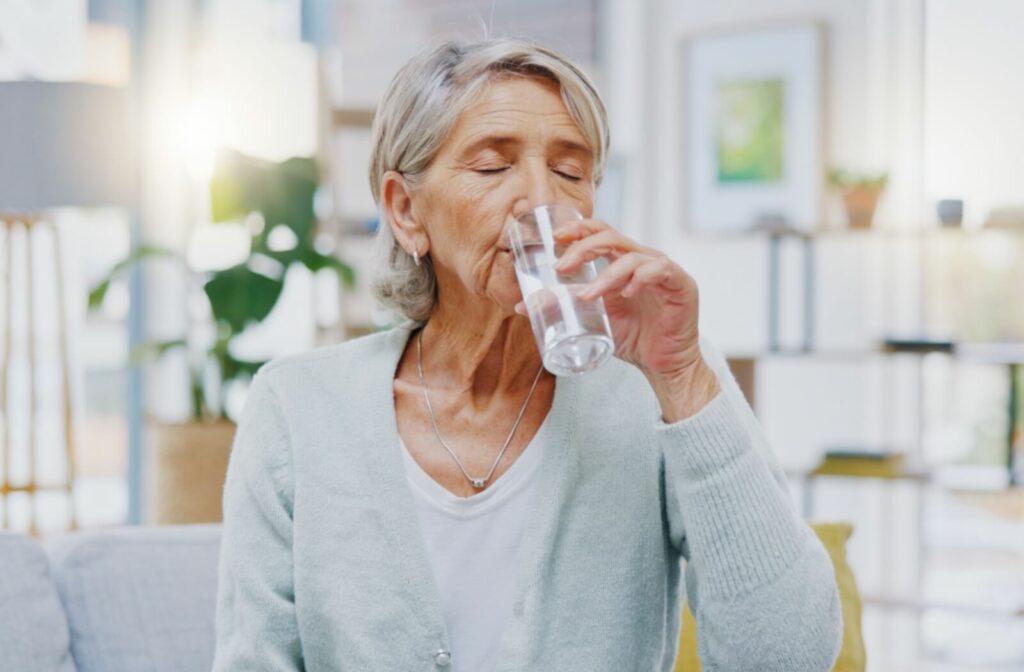 Older adult woman with Alzheimer’s drinking a glass of water.