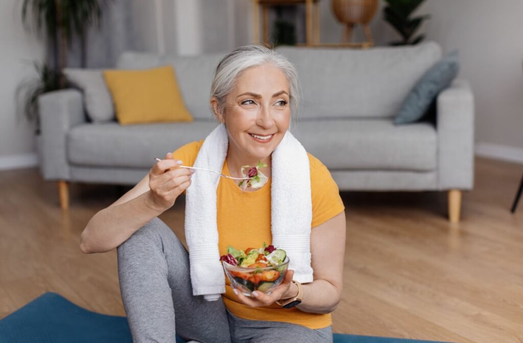 Smiling older adult taking vitamins with a glass of water.