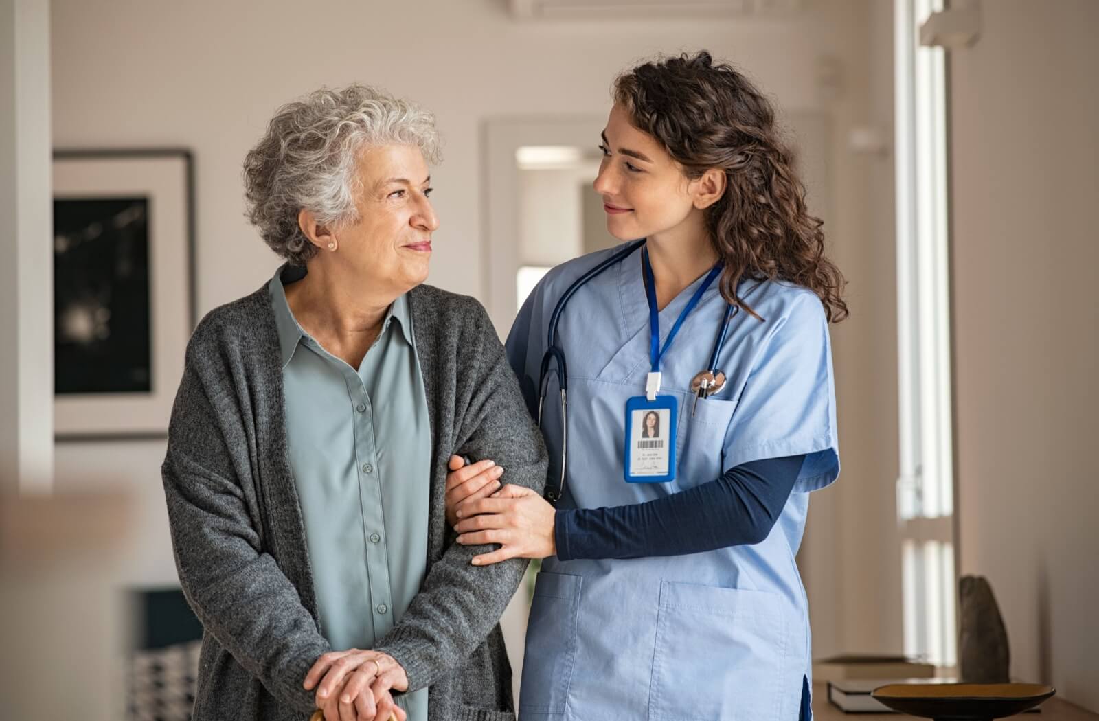 A young caregiver assists an older adult.