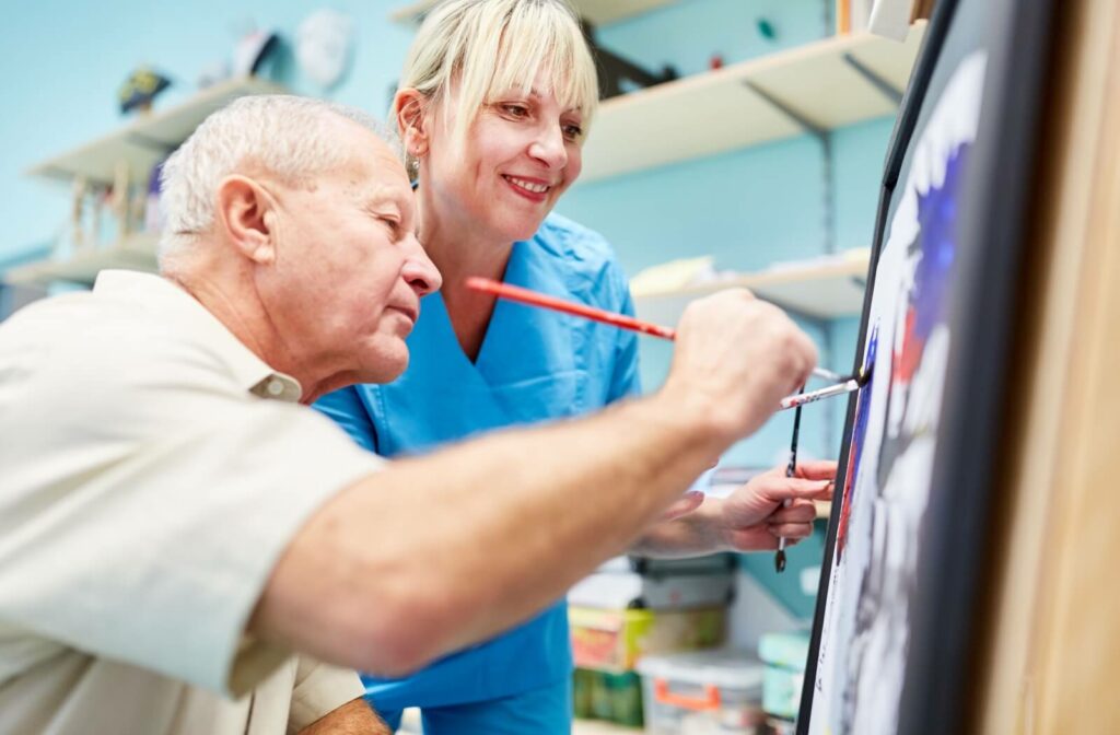 An older adult male and his therapist participate in art therapy.