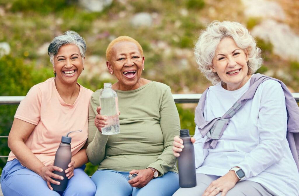 Group of older women staying hydrated and smiling after a healthy outdoor activity.