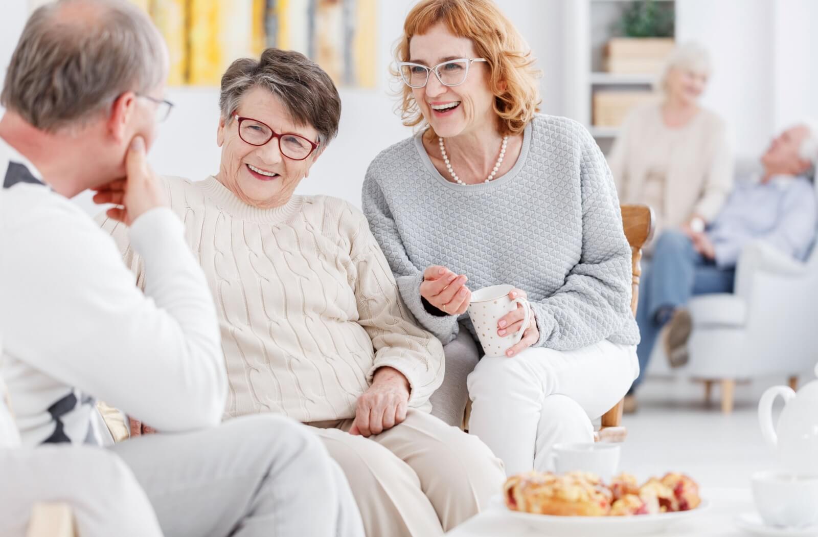 A group of older adults sitting together and laughing in independent living.