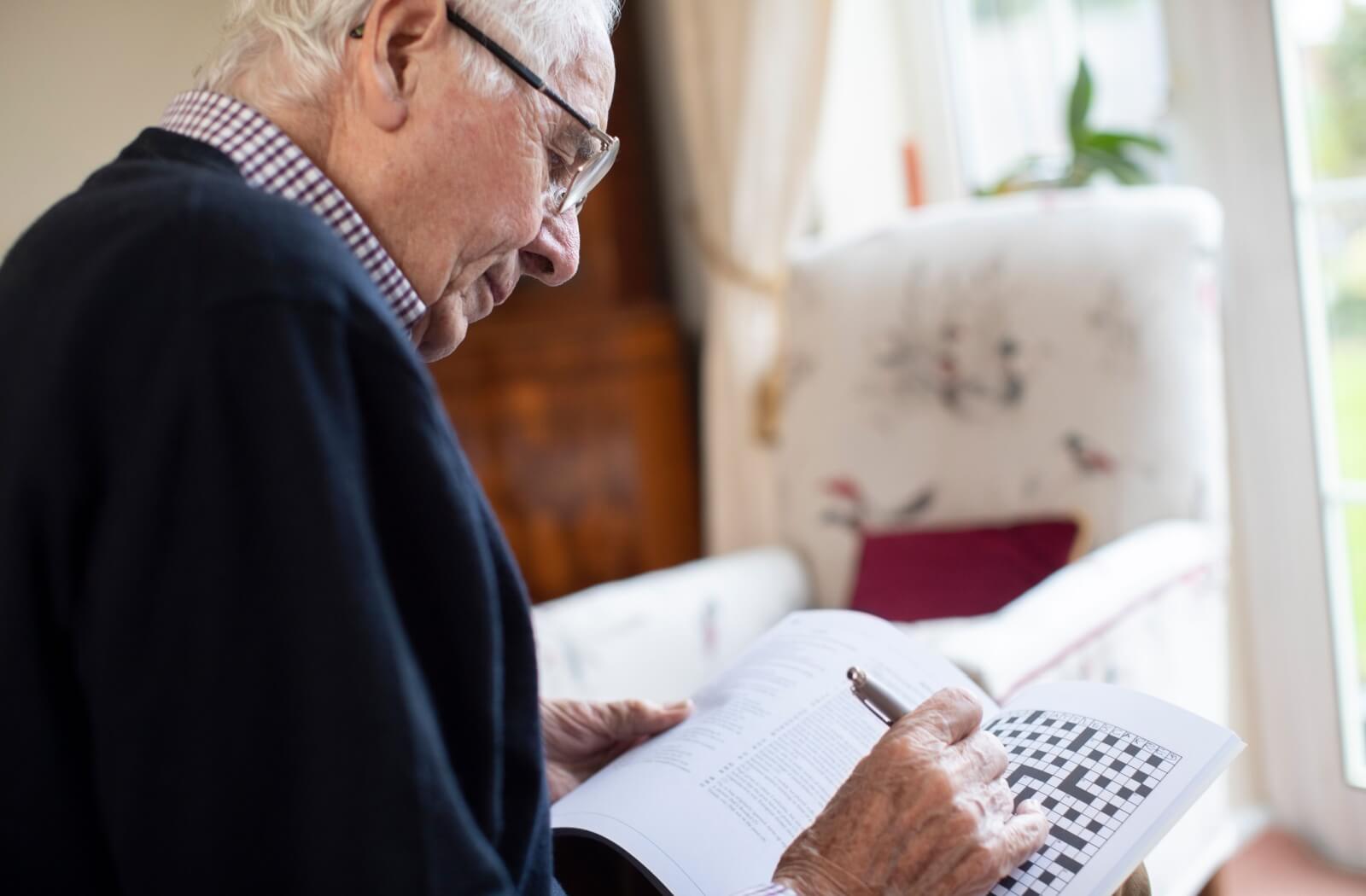 An older adult doing a crossword puzzle.
