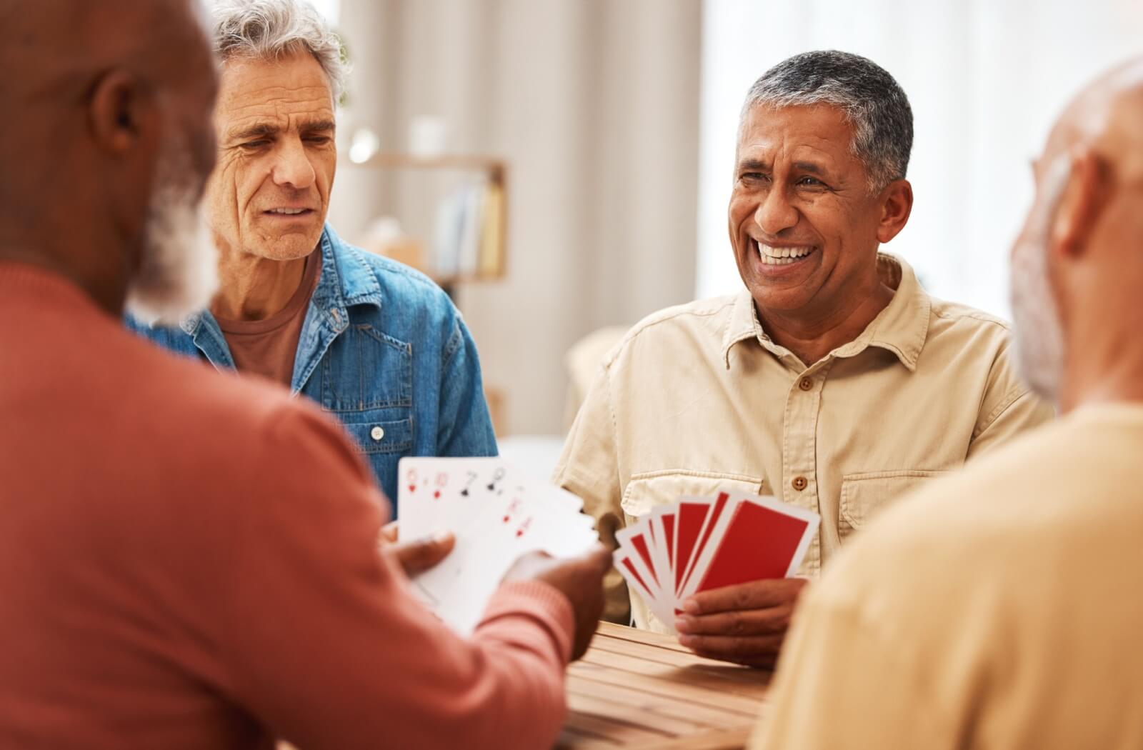 Group of older adults enjoying a card game together, smiling and engaged.