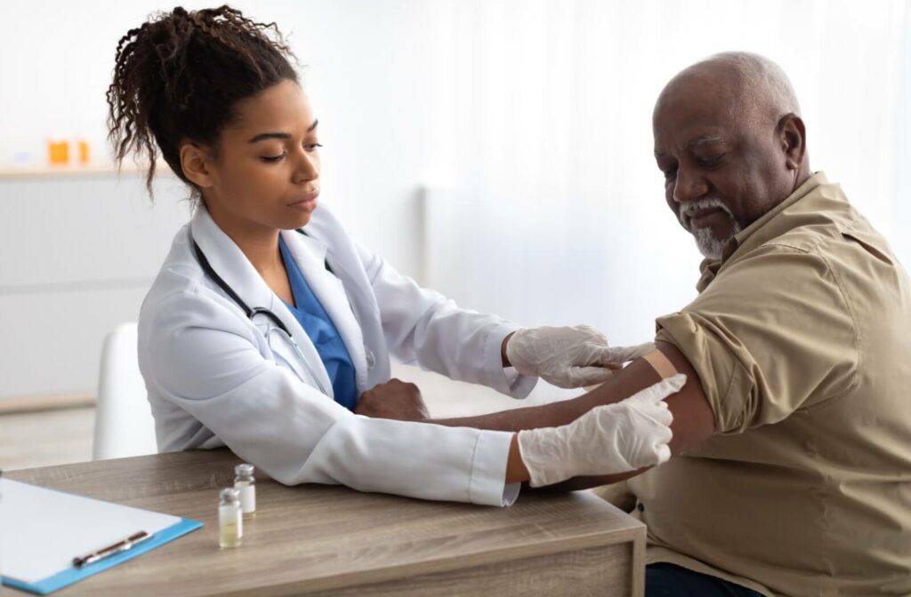 A healthcare professional gently applies a bandage to a patient's arm after administering a vaccine during a medical appointment.