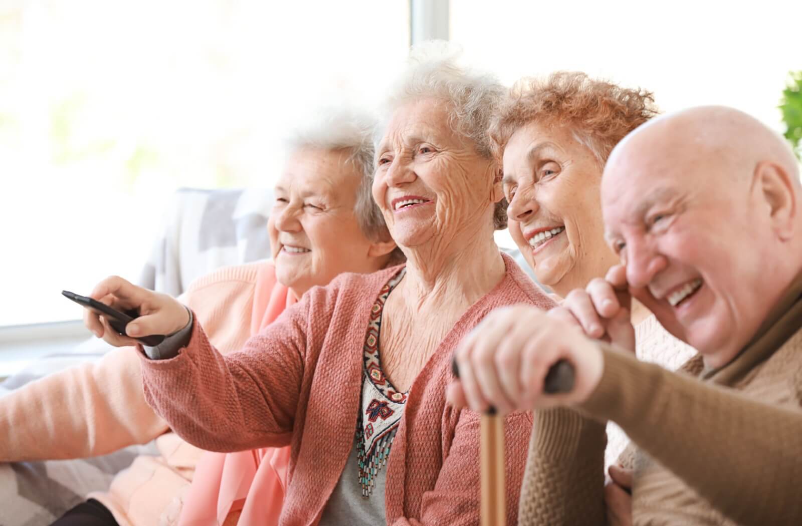 A group of happy older adults watch a movie together.