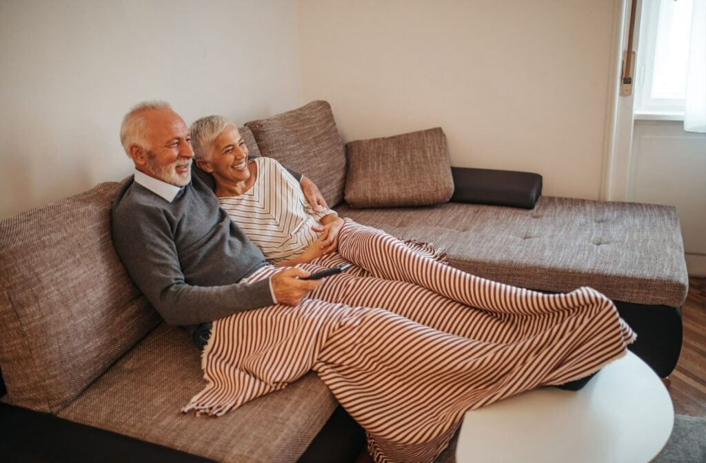 A couple lounges on the couch, watching a movie together.
