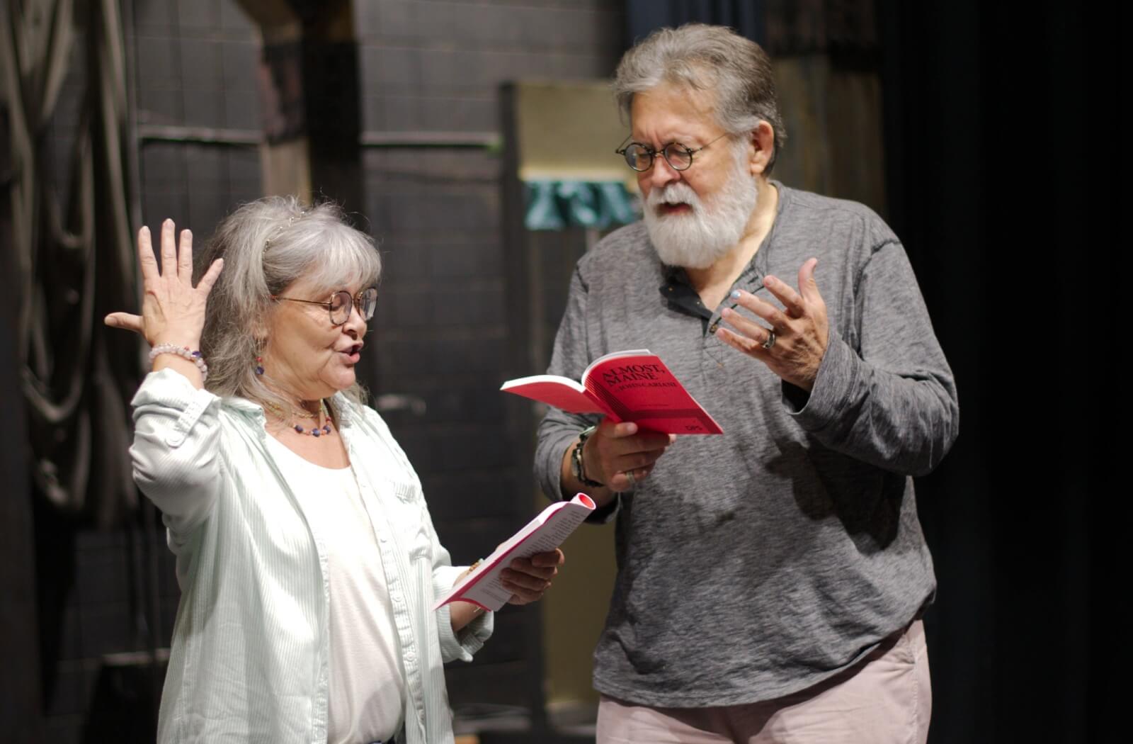 Older adults running through lines backstage before a theatre performance.