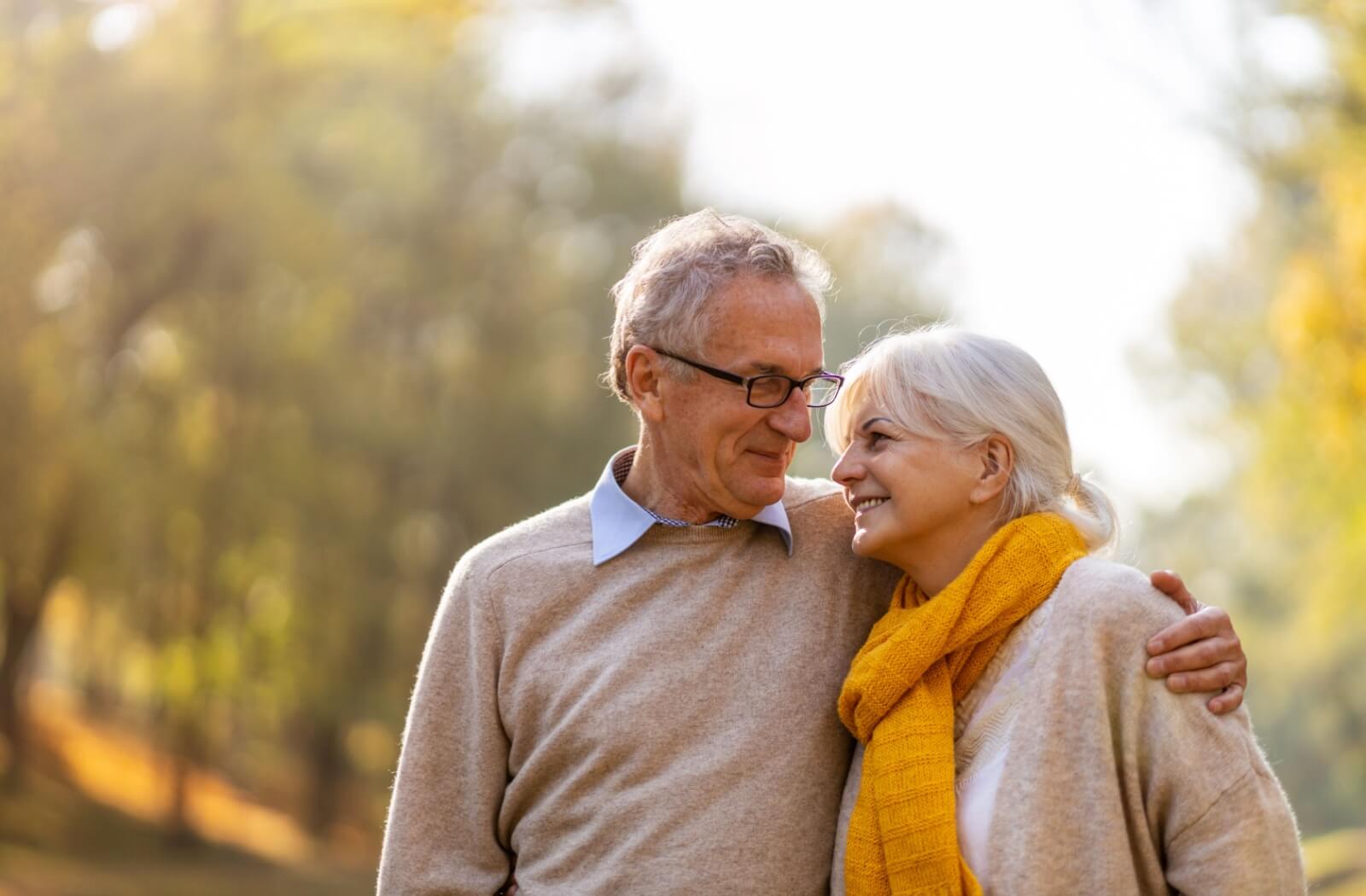An older adult couple stroll arm in arm, sharing a loving connection.