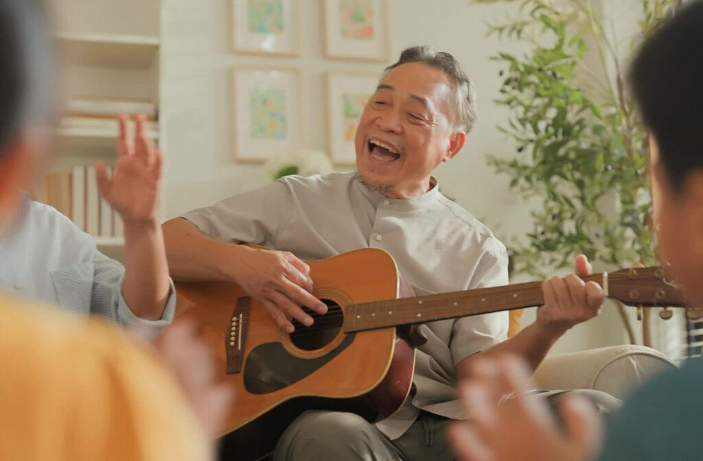 A group of older adults sing together while one plays a guitar.