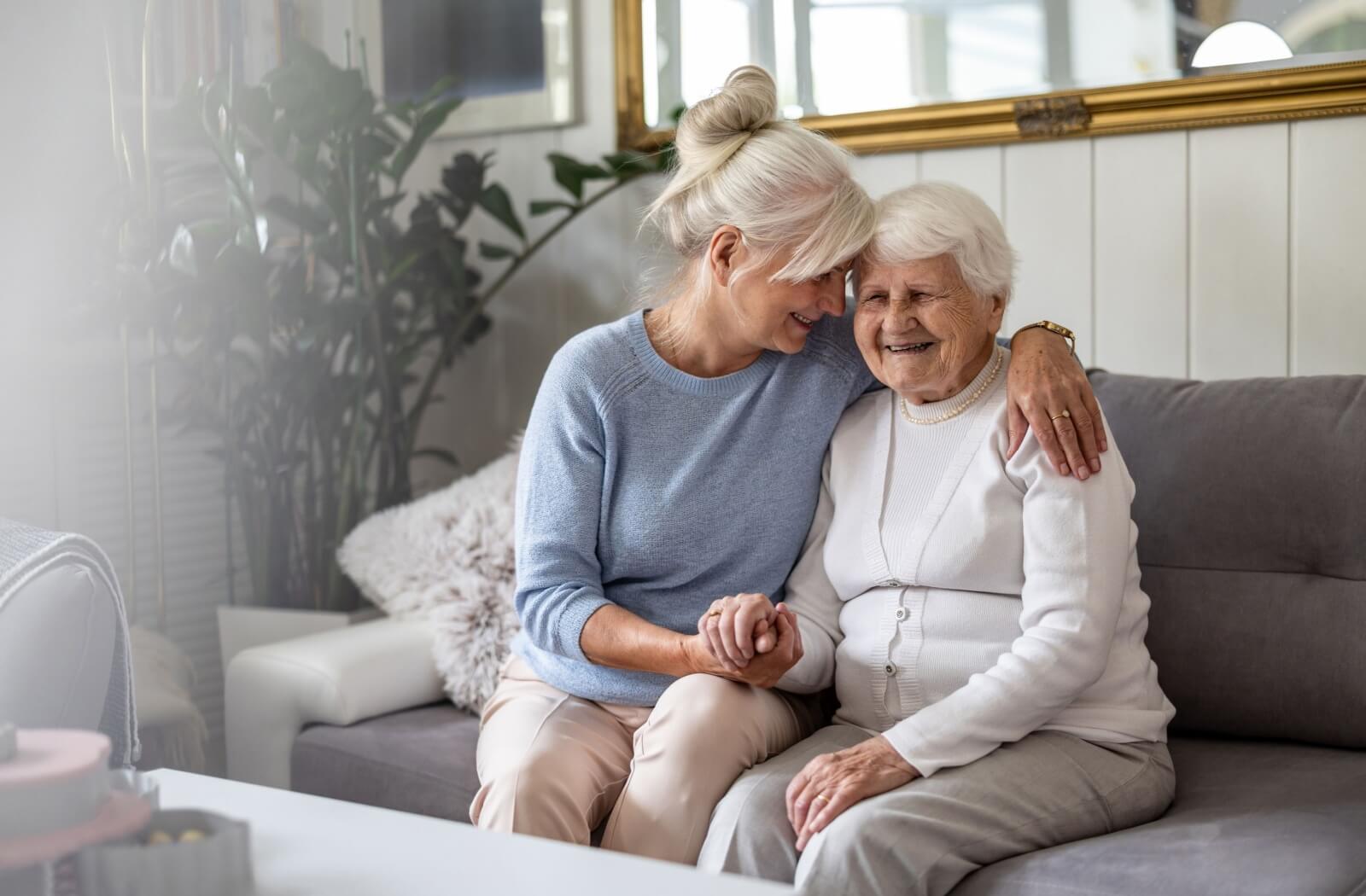 Content and relaxed older adults enjoy a warm embrace while basking in the sunlight of the living room.