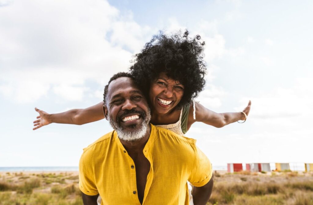 A happy older adult couple plays and laughs together outdoors.