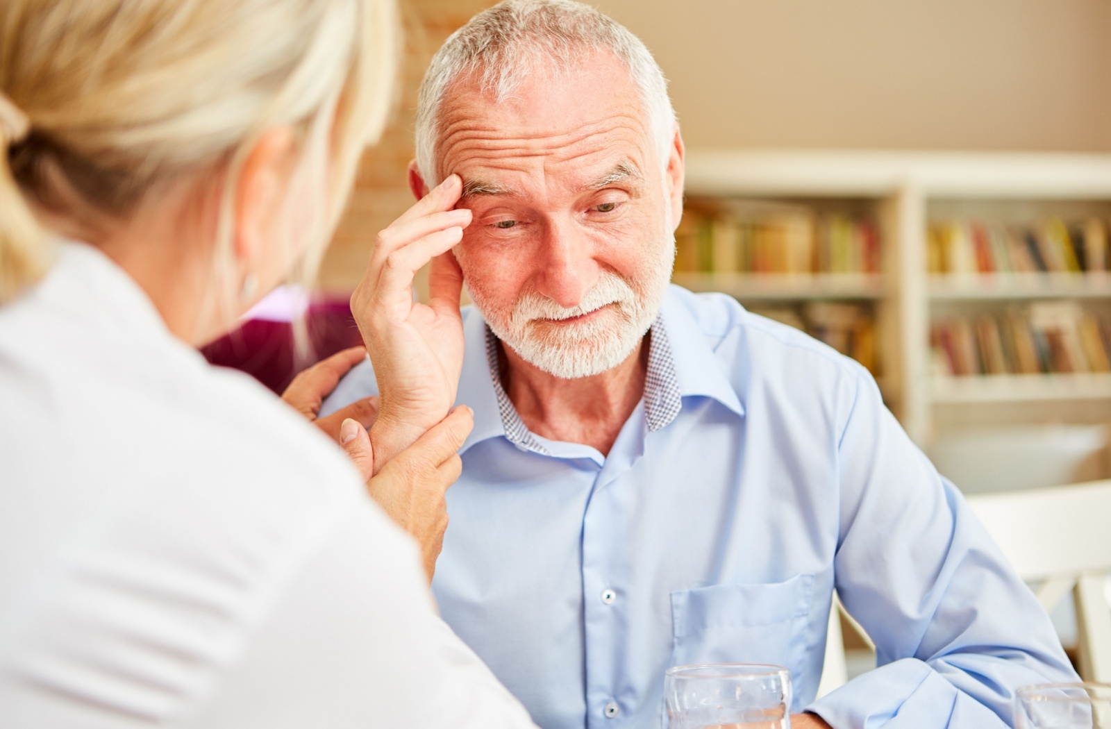 An older adult struggles with Alzheimer's symptoms while their caregiver offers support.