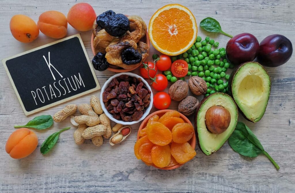 A chalkboard that says potassium is surrounded by a variety of foods that contain potassium.